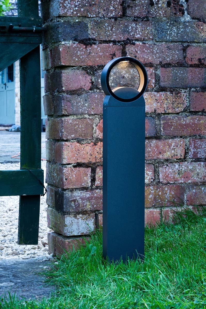 Reon outdoor LED post light on grass in front of red brick wall